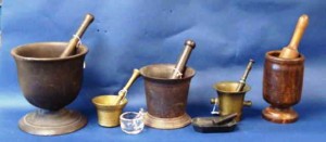 blogpharmacya The large, iron pedestal mortar and pestle on the left was one used on the counter of an apothecary. Current auction prices range from (left to right) $95 for large cast iron pedestal, $50-100 for the small brass, $20 for the tiny 18th-century glass, $50 for the medium cast iron, $175 for the brass, and $85 for the lignum vitae.