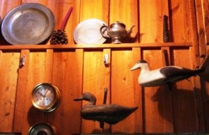 blogdecoydecor6 These decoys are mounted on the wall using hand forged iron L brackets. The decoy on the left is a Mitchell Black Duck and the black and white decoy is an Eider from Maine. Also on the cypress board and batten wall is a Chelsea clock and barometer with a pewter collection on the shelf above.
