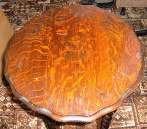 This turn-of-the-century oak table top sure looks-well worn by long handling – and abuse. It still probably qualifies as having patina.