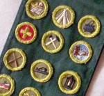 vintage-boy-scout-sash-with-16-badges-1950e28099s A collection of 1950s-vinatge Boy Scout merit badges on a sash, including Reading, Camping, Cooking, First Aid, Home Repair, World Brotherhood, Canoeing, Carpentry, Metalwork.