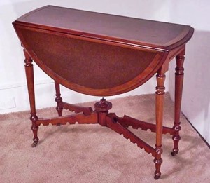 mechanical-walnut-drop-leaf-game-table This may look like an ordinary drop leaf table, but it has a unique mechanical feature. The table was originally designed for card or game playing. This card table has an inset leather top. When the leaves are down, it only measures 12 and a half inches wide. By raising both leaves at the same time, two legs are spring-loaded and automatically swing out to support the leaves. Circa 1880.