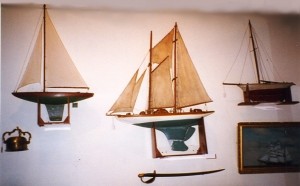 blogpondboats Three pond yachts are displayed on a wall at a show in Greenville, SC. Also in the picture are a telltale compass, an 1860 model cutlass, and a ship diorama. This gives good ideas for displaying these beautiful items in your home.