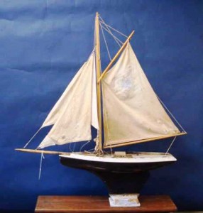 blogpondmodel8 This is a hollow hull constructed gaff rigged pond yacht with iron at the bottom of the wooden keel instead of lead. It is 31 inches long and 28 inches tall and still has its patched and well-used sails. Look at the very simple stand for this model yacht. Value in a retail setting is about $575.