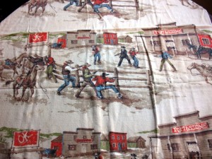 barkcloth3 This novelty print depicts a cowboy shoot-out. Notice the OK Corral sign and Tombstone sign on the building. Cowboy prints are very desirable.